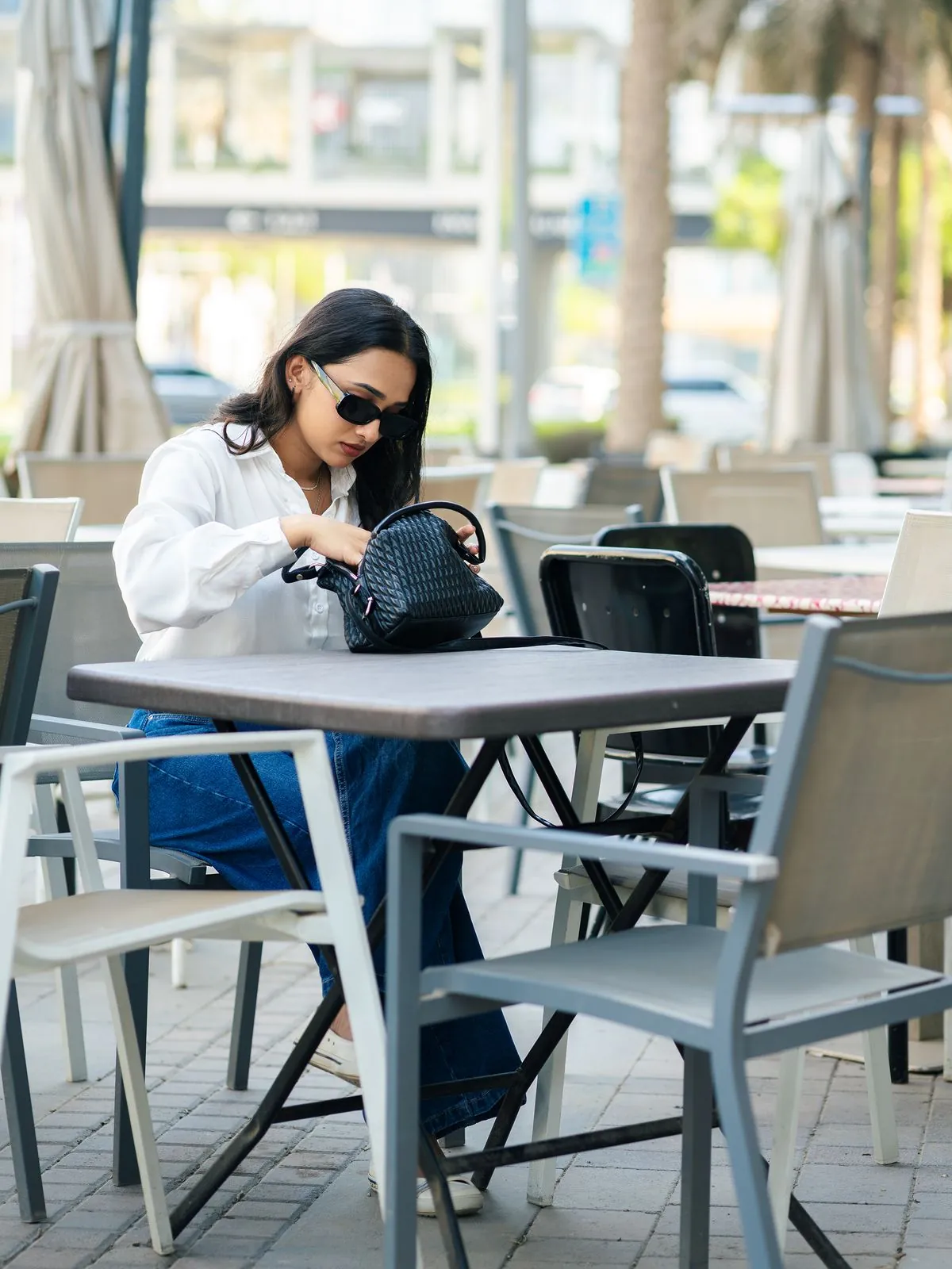 Relaxed lifestyle image of a model seated at a café table, natural light, from a published YKS shoot